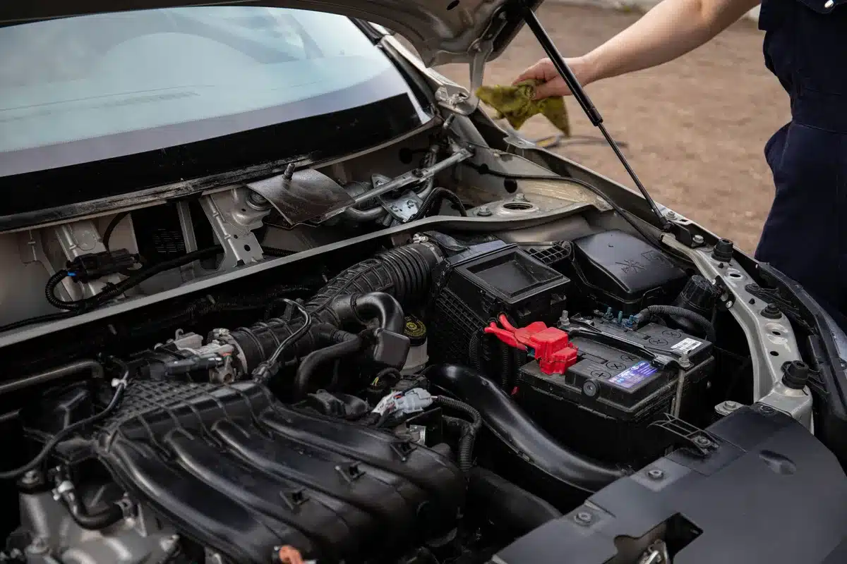 Car engine compartment with battery terminals, close-up view, ready for jump start connection