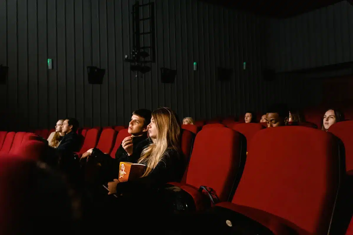 Gente en la taquilla de un cine con boletos y palomeras