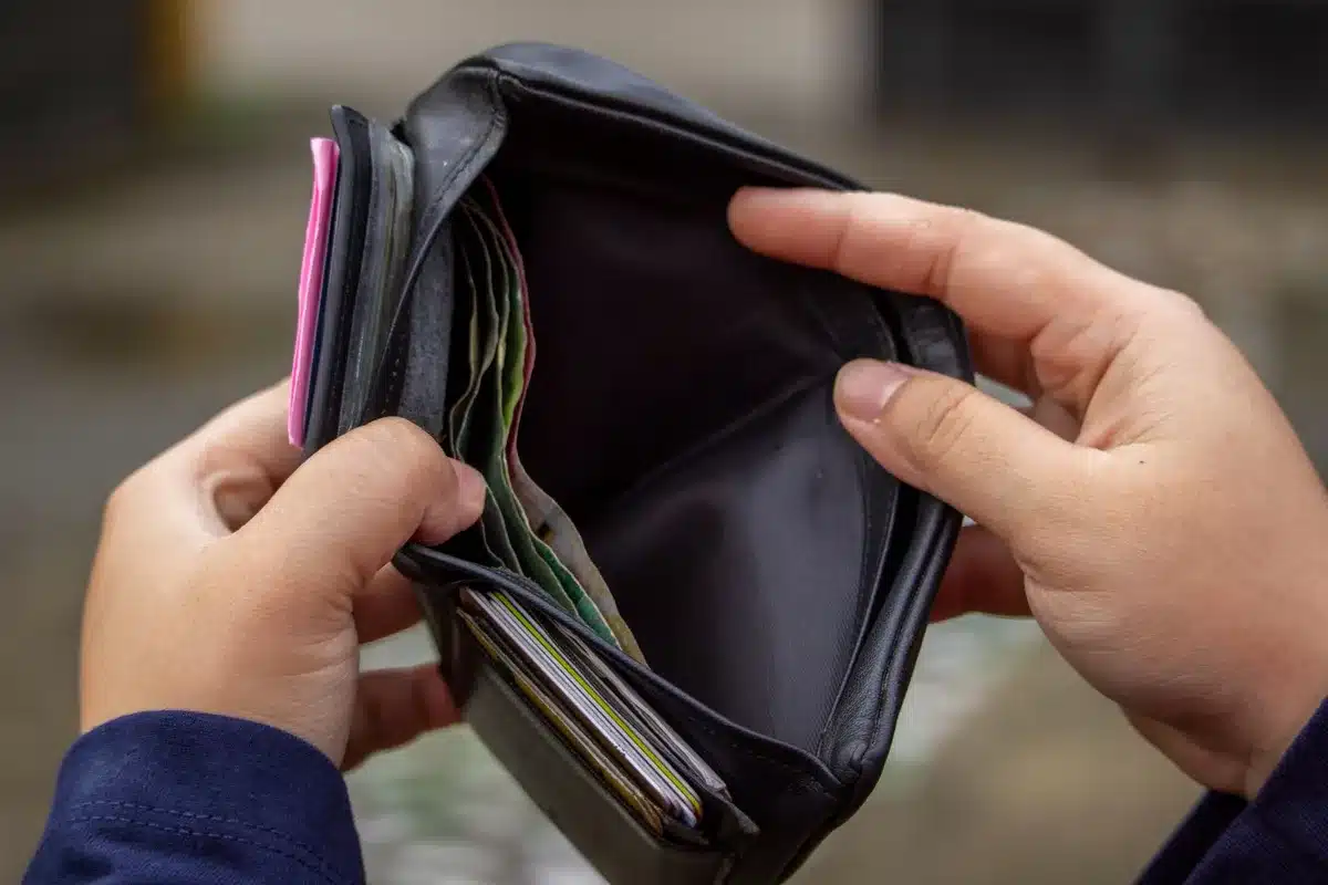 Billetera vacía o con poco dinero junto a recibos de compra y etiquetas de precios
