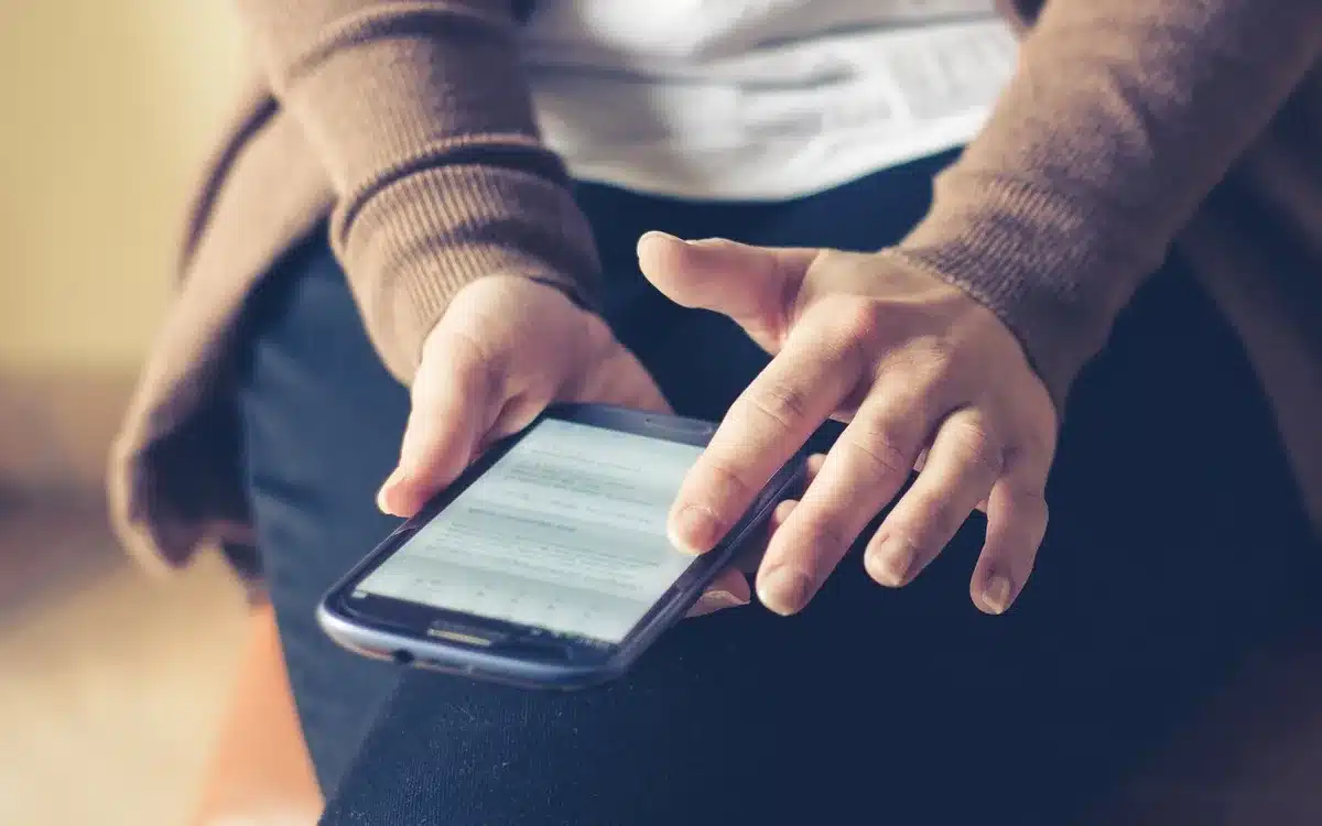Smartphone screen displaying CFE Internet plan options with price list and data amounts, hands holding device showing activation interface, bright mobile screen in focus