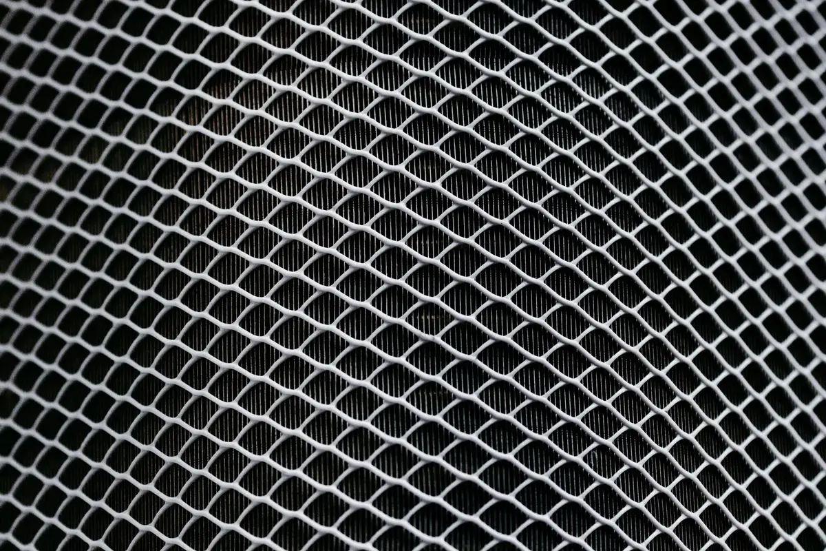 Close-up of the electrostatic filter component showing fine fibers with a subtle glow, next to a dark activated carbon filter pad on a neutral background