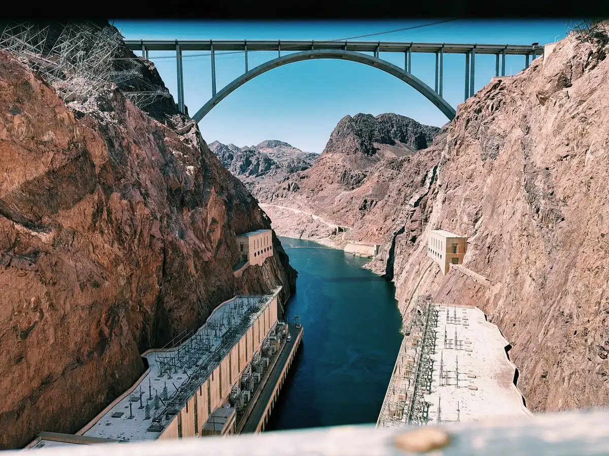 Represa hidroeléctrica con niveles bajos de agua durante sequía, ilustrando riesgos en generación de energía.
