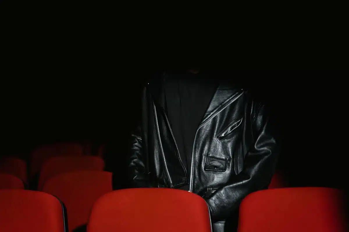 Público en sala de cine viendo una película de terror, con pantalla iluminada de fondo