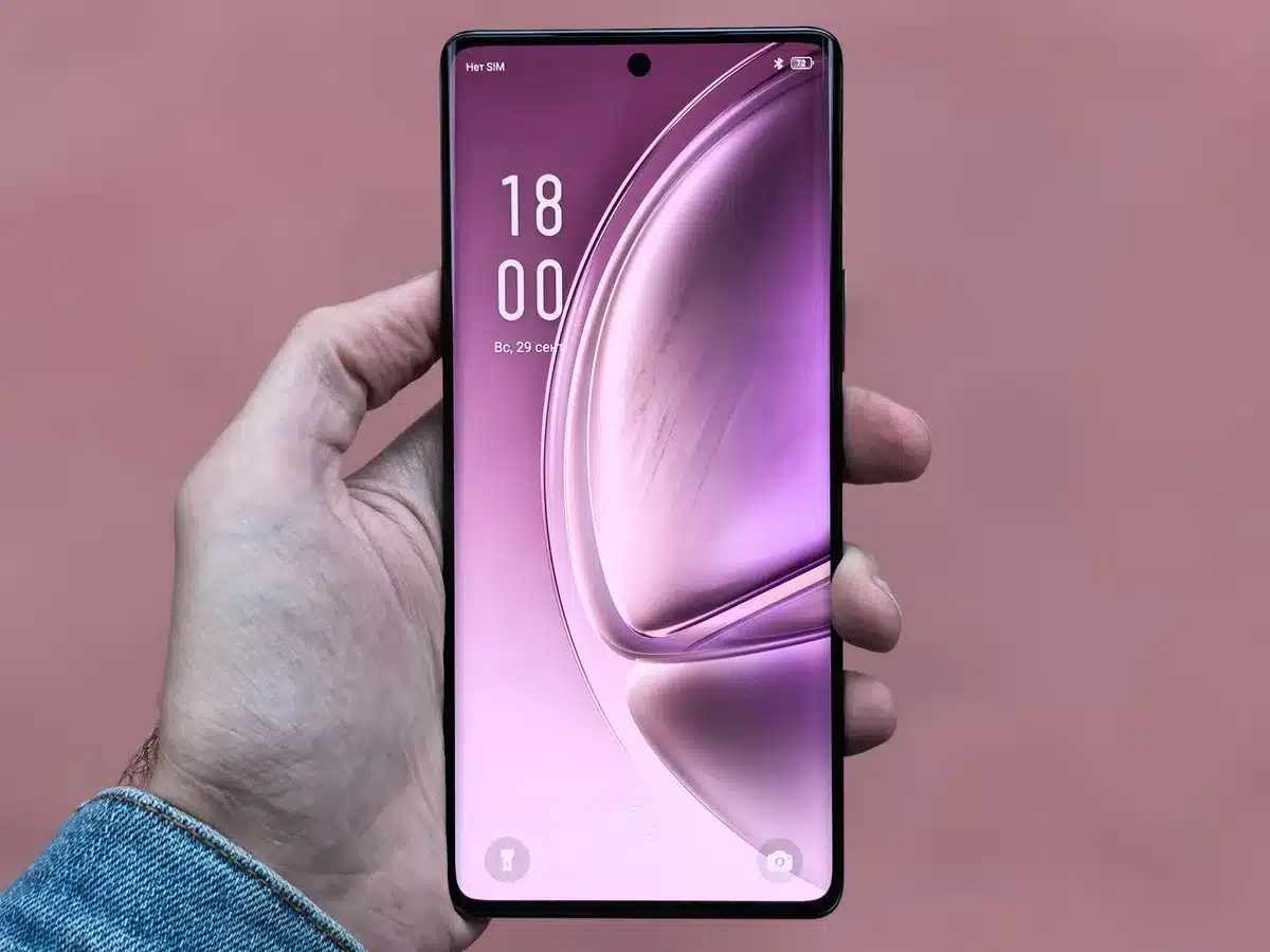 Manos sosteniendo un teléfono plegable abierto con pantalla dual activa en un escritorio moderno