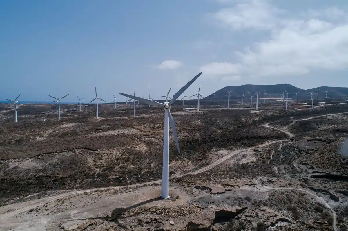 Horno industrial de cemento con turbinas eólicas y paneles solares de fondo, simbolizando la transformación hacia produc