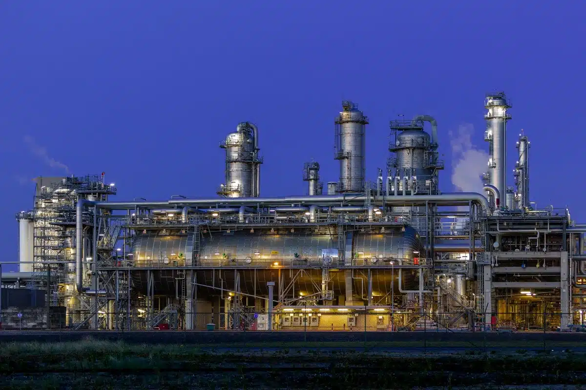 Refinería de petróleo con instalaciones industriales iluminadas de noche
