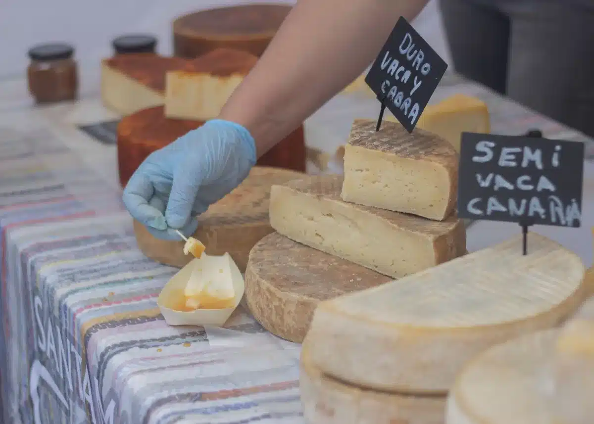 Trade negotiation documents spread across a table with cheese samples and flags of Mexico, US, and EU in soft focus, representing the complex diplomatic dispute