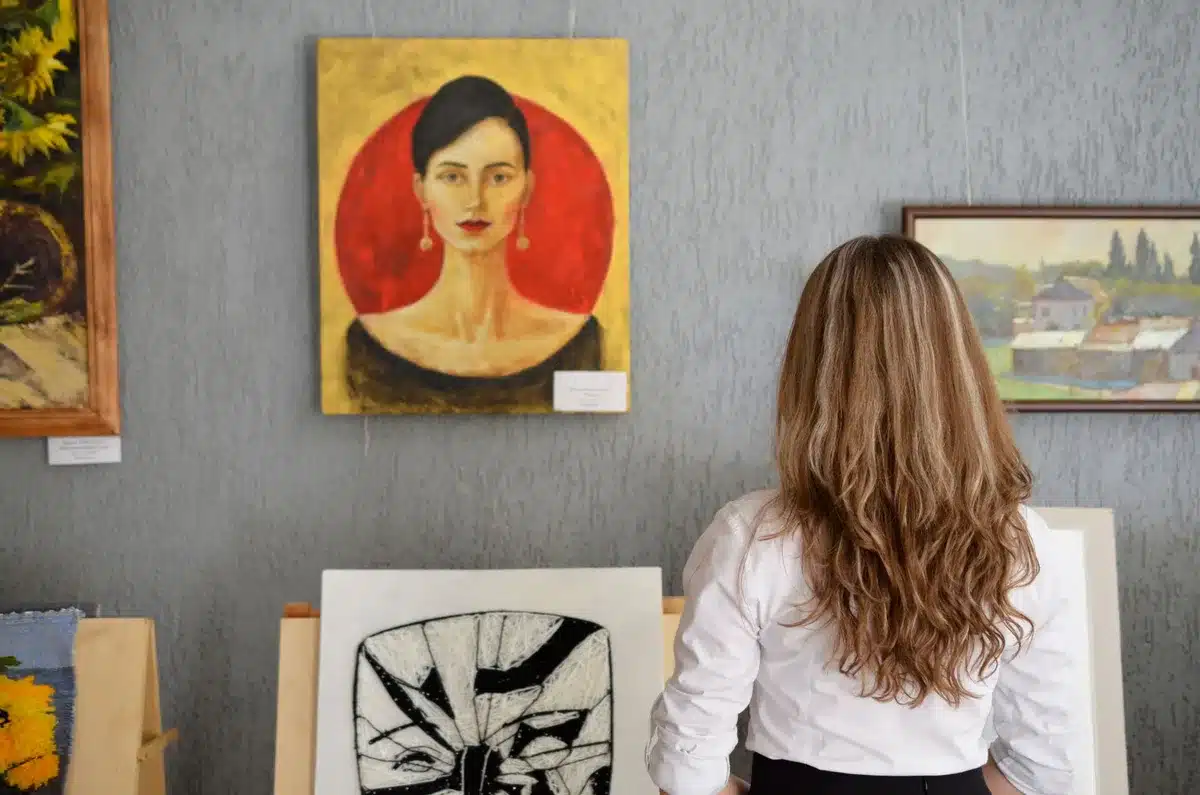 Galería de arte con obras en paredes y luz tenue, oficial de policía inspeccionando el espacio