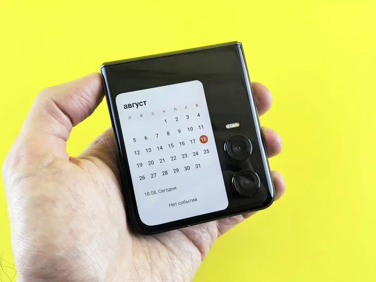 A sleek foldable smartphone displayed open, showing its expansive internal screen, with a minimalist tech store setting and soft lighting emphasizing the premium design and dual-screen functionality