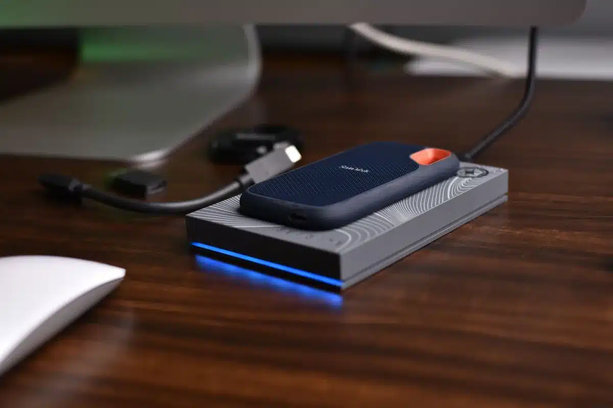 Sleek metallic external SSD with magnetic attachment sitting on a desk next to a smartphone, showing the compact form factor and modern design of portable storage technology