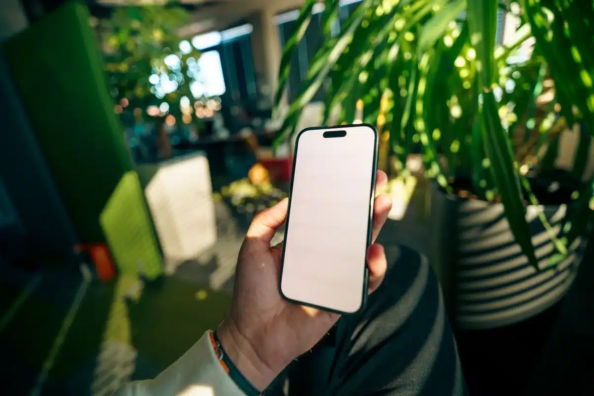 Foldable smartphone with wide internal display in tablet-like aspect ratio, perforated camera in corner, horizontal rear camera module with three lenses visible, thin profile, dark red finish, unfolded position showing full screen