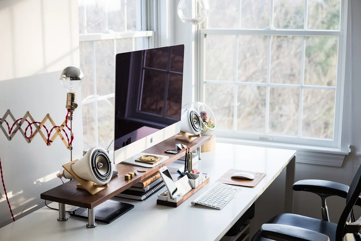 an empty modern office desk with a laptop, access badge and notebook suggesting ongoing review work