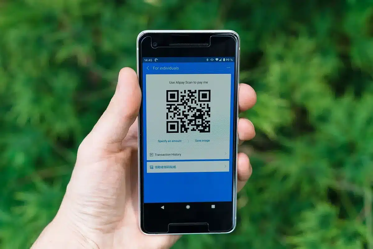 Anonymous hands holding a credit card over a phone screen showing a payments app, no brand visible