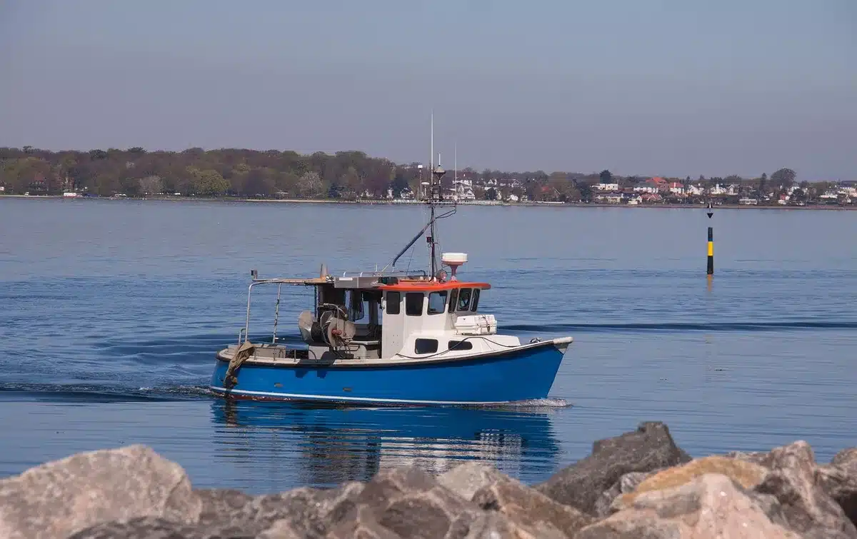 Anonymous small fleet of fishing boats tied at a quiet pier at dawn, empty decks and stacked gear visible