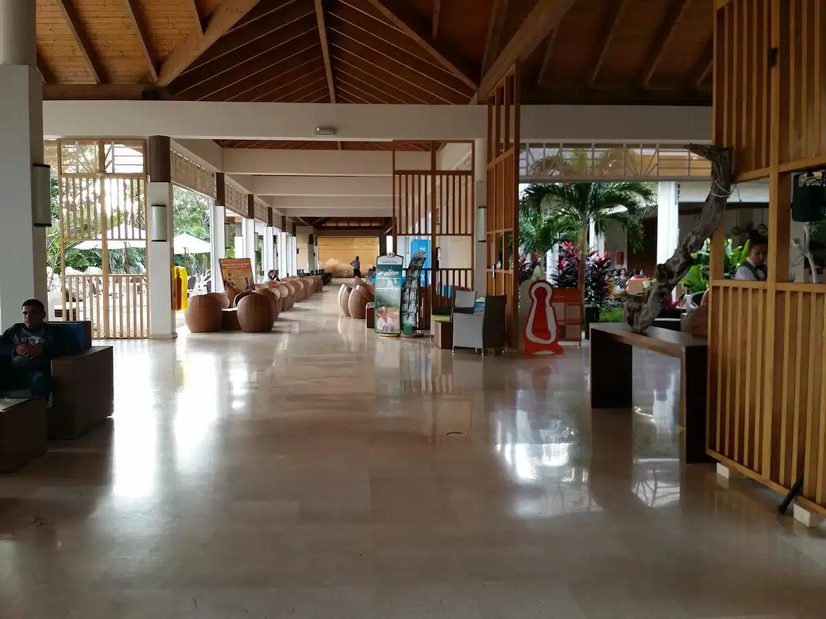 A hotel lobby with minimal guests, soft ambient lighting, empty check-in desk, few people visible, conveying a quiet, slow business period.