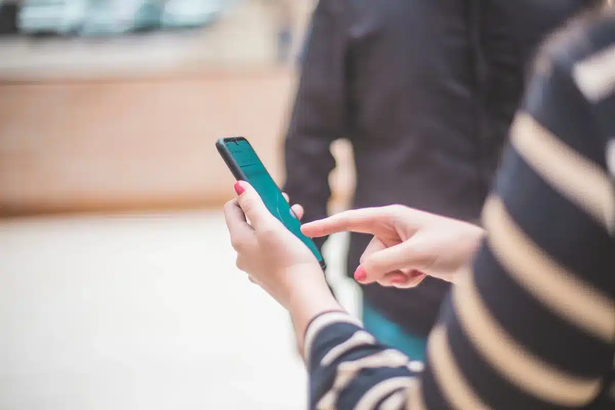 anonymous hands scrolling social app on an unbranded phone with bright AMOLED screen visible, blurred background, no faces