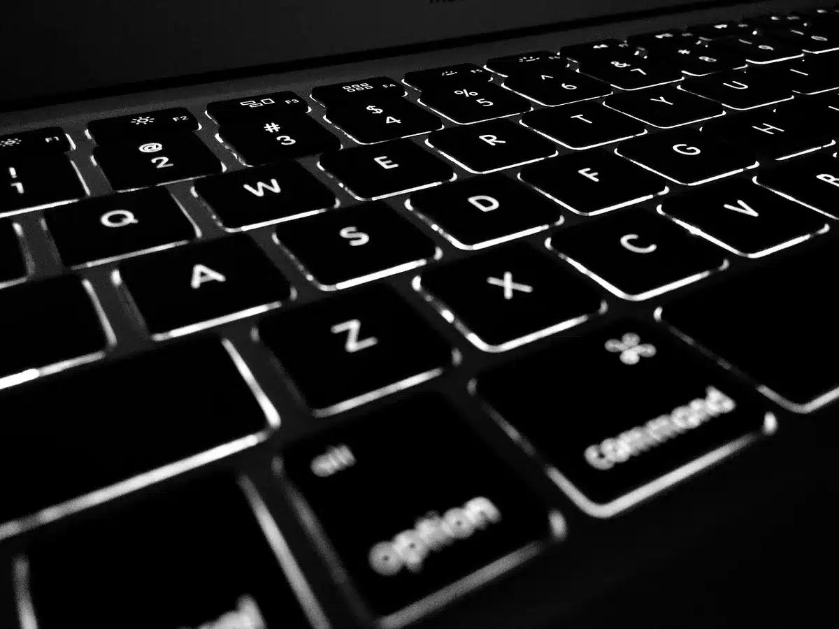 A close-up view of a developer's hands typing on a keyboard while a glowing screen displays verbose AI-generated code comments and explanations. The lighting creates a sense of focused intensity.