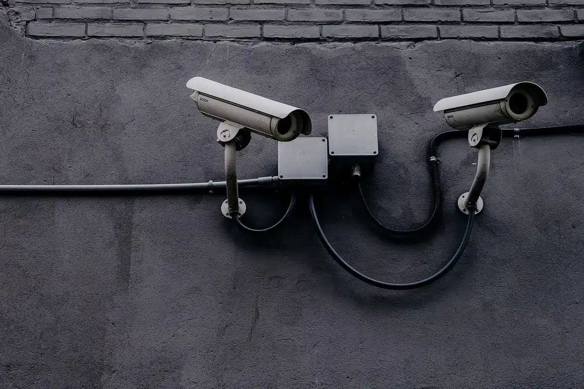 Cámaras de vigilancia de tráfico instaladas en una calle urbana con vehículos anónimos pasando.