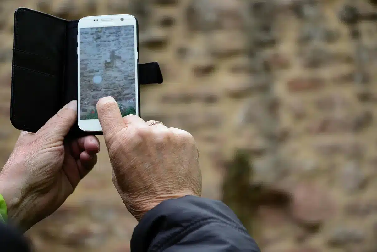 Manos sosteniendo un teléfono anónimo sobre una mesa en estudio, enfoque en la silueta y cámara