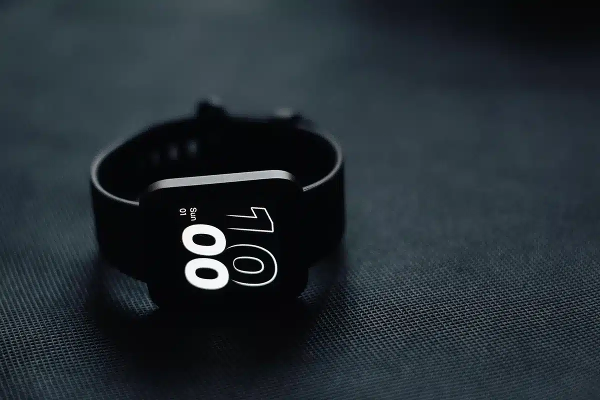 A medical-grade smartwatch display showing blood pressure reading with a pulsing heartbeat animation, captured in warm clinical lighting against a blurred healthcare background