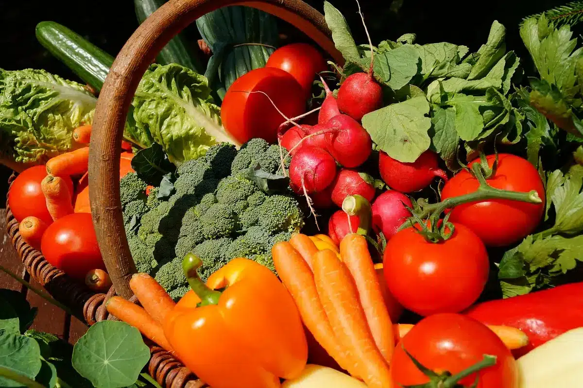 Puesto de mercado con tomates, lechuga y verduras frescas en cajas de madera.