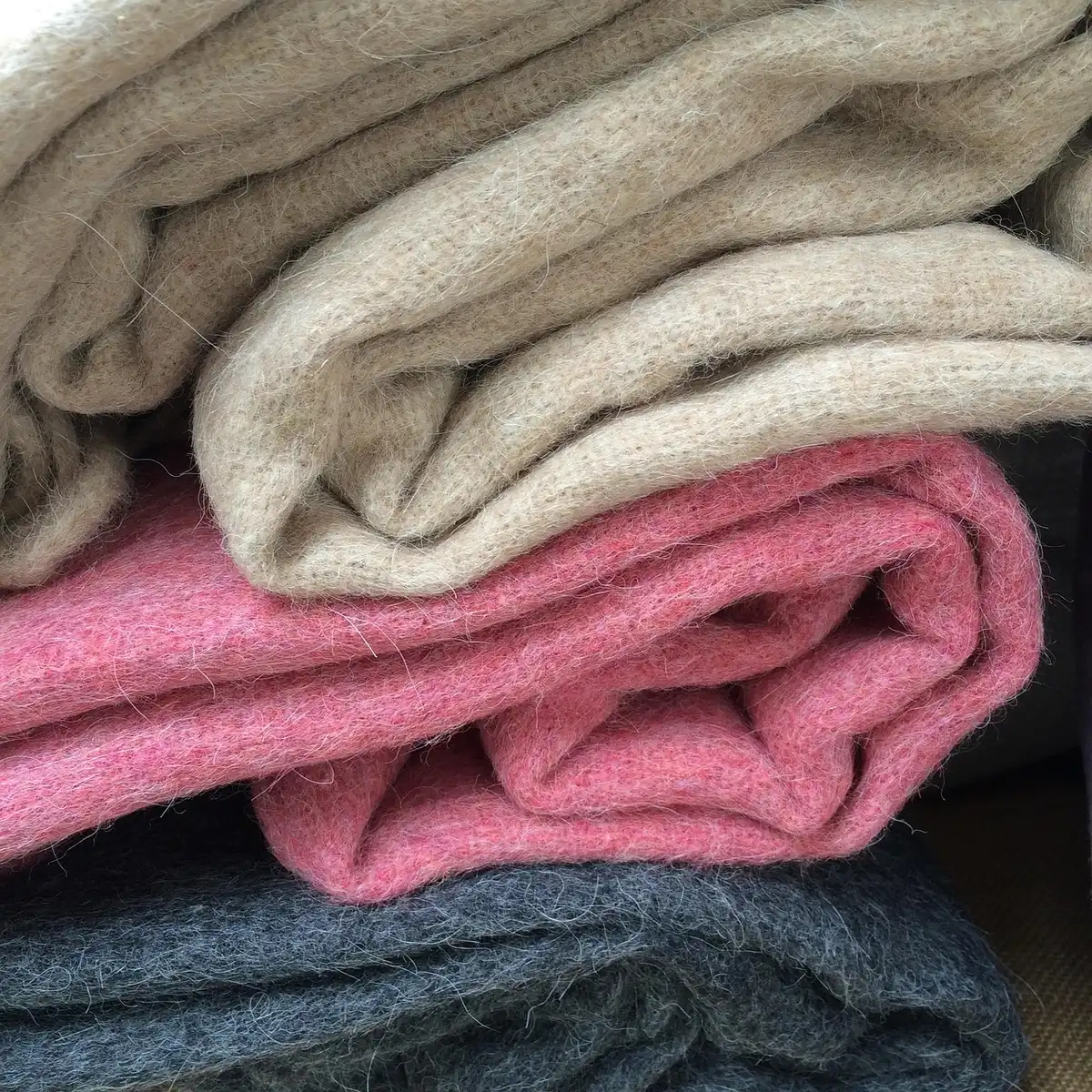 An expanse of wool blankets laid across a snowfield, textured fiber visible, no logos or people, alpine peak in the background