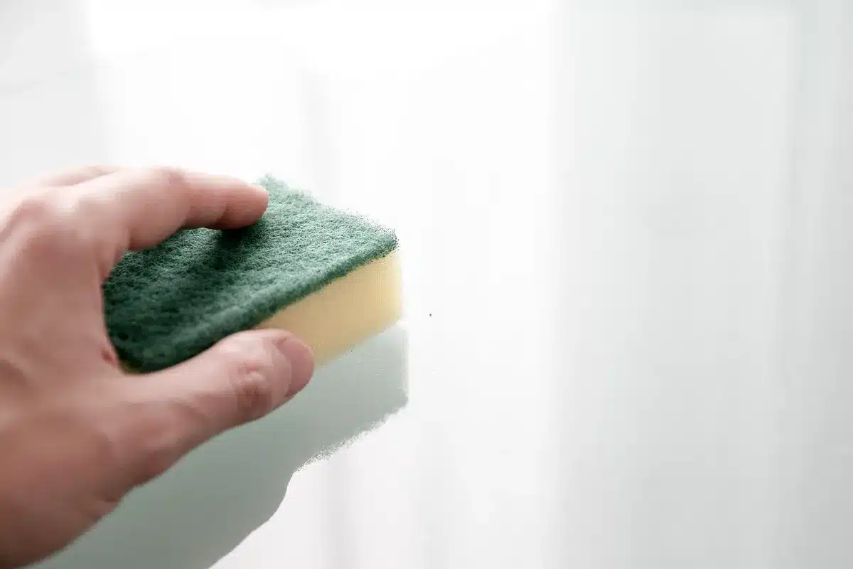 Person's hands gently wiping a dark TV screen with microfiber cloth, one-directional motion, soft lighting