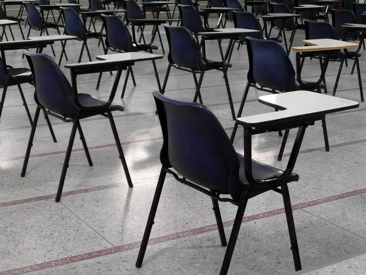 An empty modern classroom with desks, unbranded laptops on some desks, a whiteboard filled with diagrams, no students, late-afternoon light