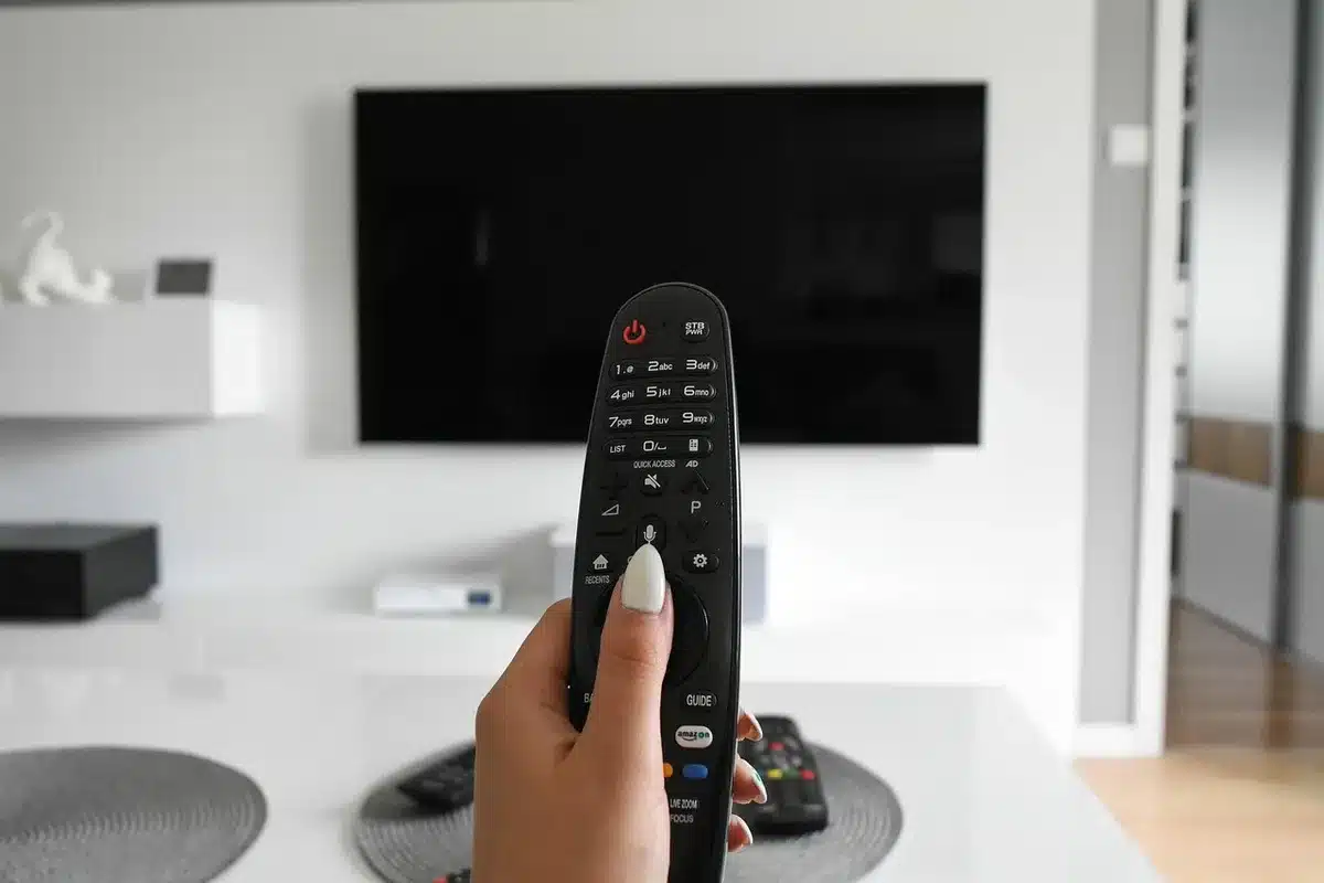 Wide shot of an anonymous living room with a TV and a smartphone on a table showing a paused football match, no logos or identifiable faces