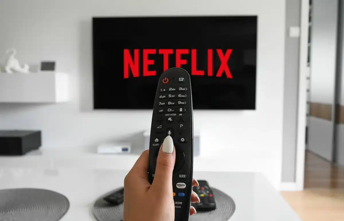 Mano sosteniendo control remoto y pantalla mostrando una serie en streaming