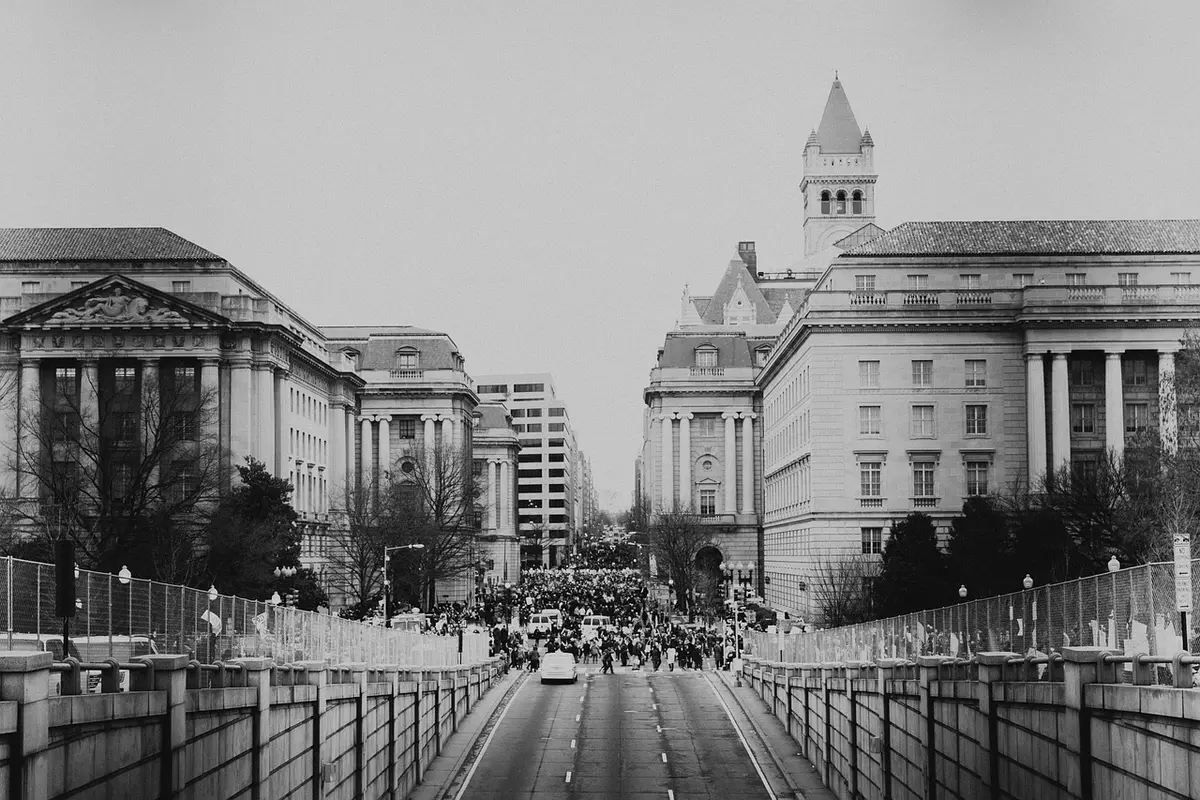 A dimly lit political rally with anonymous supporters holding campaign materials and signs, faces obscured in shadow, tension and campaign fervor visible in raised arms and gestures