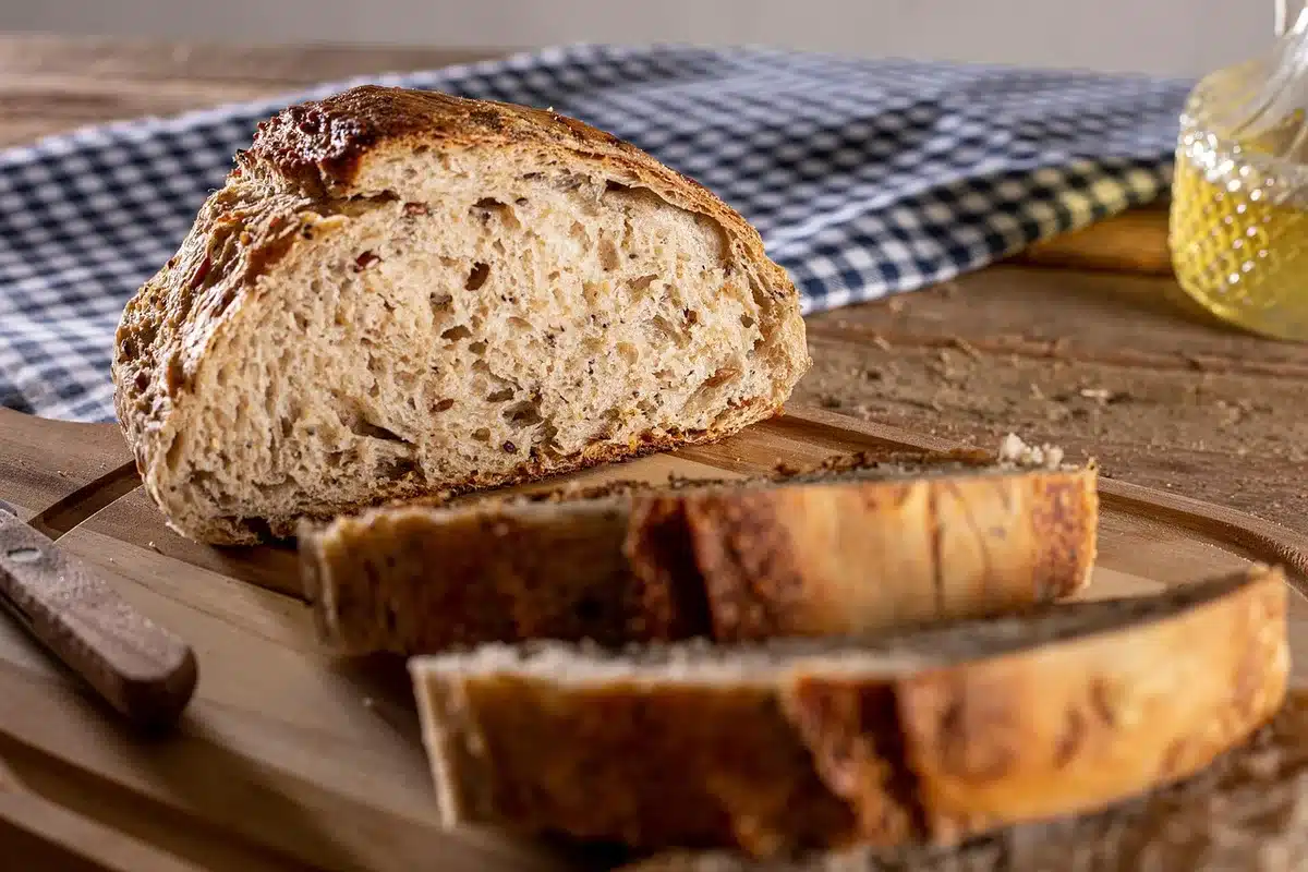 Artisan bread varieties displayed on wooden boards in a market stall, showing traditional Mexican sweet breads in warm, golden tones with morning light