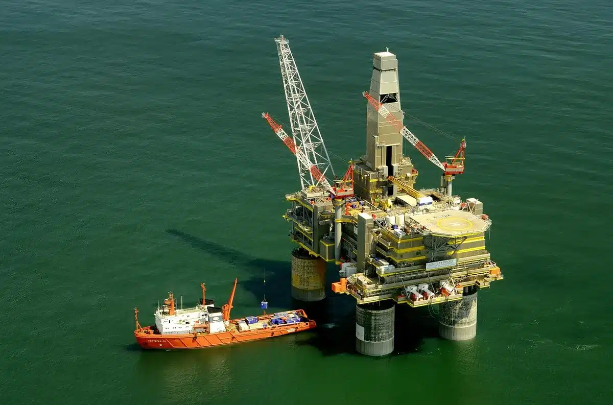 Wide shot of an empty offshore work platform at dawn with cranes and winches, maintenance vessels nearby, no people visible