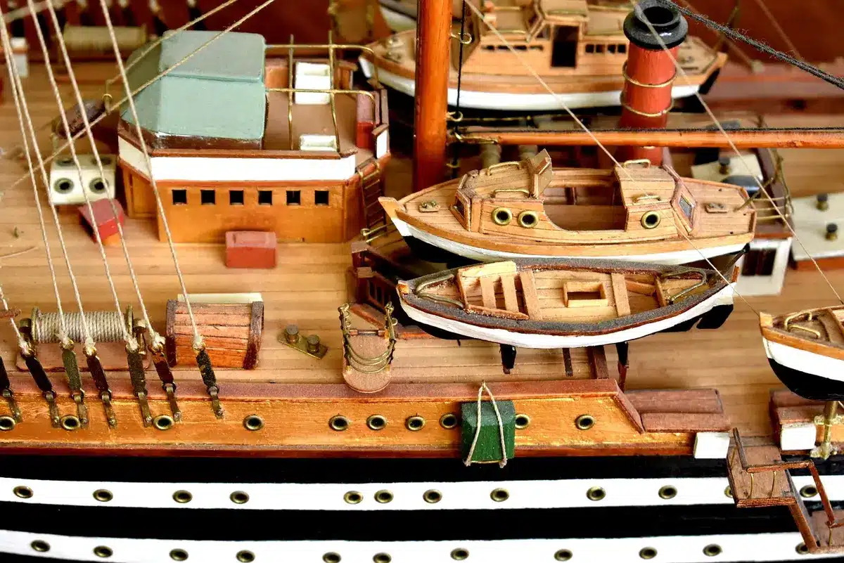 Close-up of an anonymous maintenance crew's hands handling a thick unbranded cable on a ship deck, tools and safety gear visible but no faces