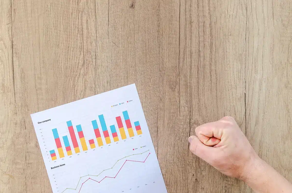 Manos sobre un portátil y gráficos en un despacho que sugieren actividad económica