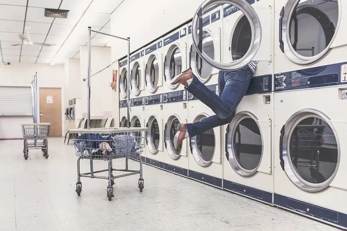 A front-load washer-dryer combo in white or gray, modern minimalist design, displayed in a compact laundry space with clean lines and soft lighting