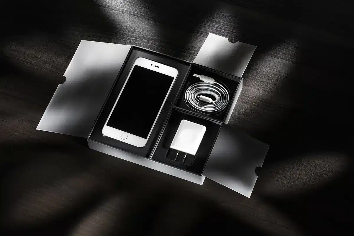 A compact, cube-like desktop charger on a clean desk, small digital screen glowing, several USB-C cables plugged in, anonymous hands reaching for a cable