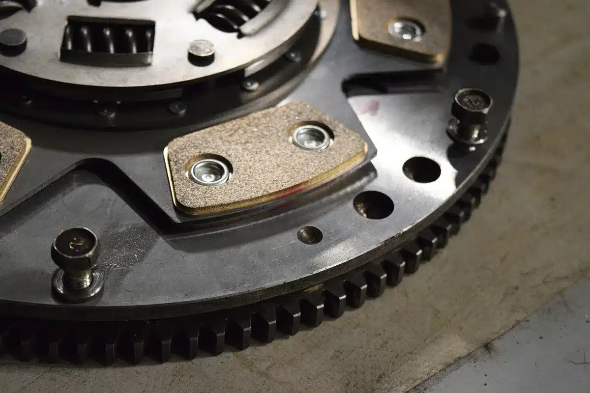 A workbench with anonymous mechanics' gloved hands inspecting a cleaned car component, diagnostic tools nearby