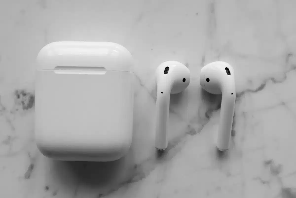 close-up of an unbranded wireless earbuds case open on a table, charging cable beside it, no logos visible
