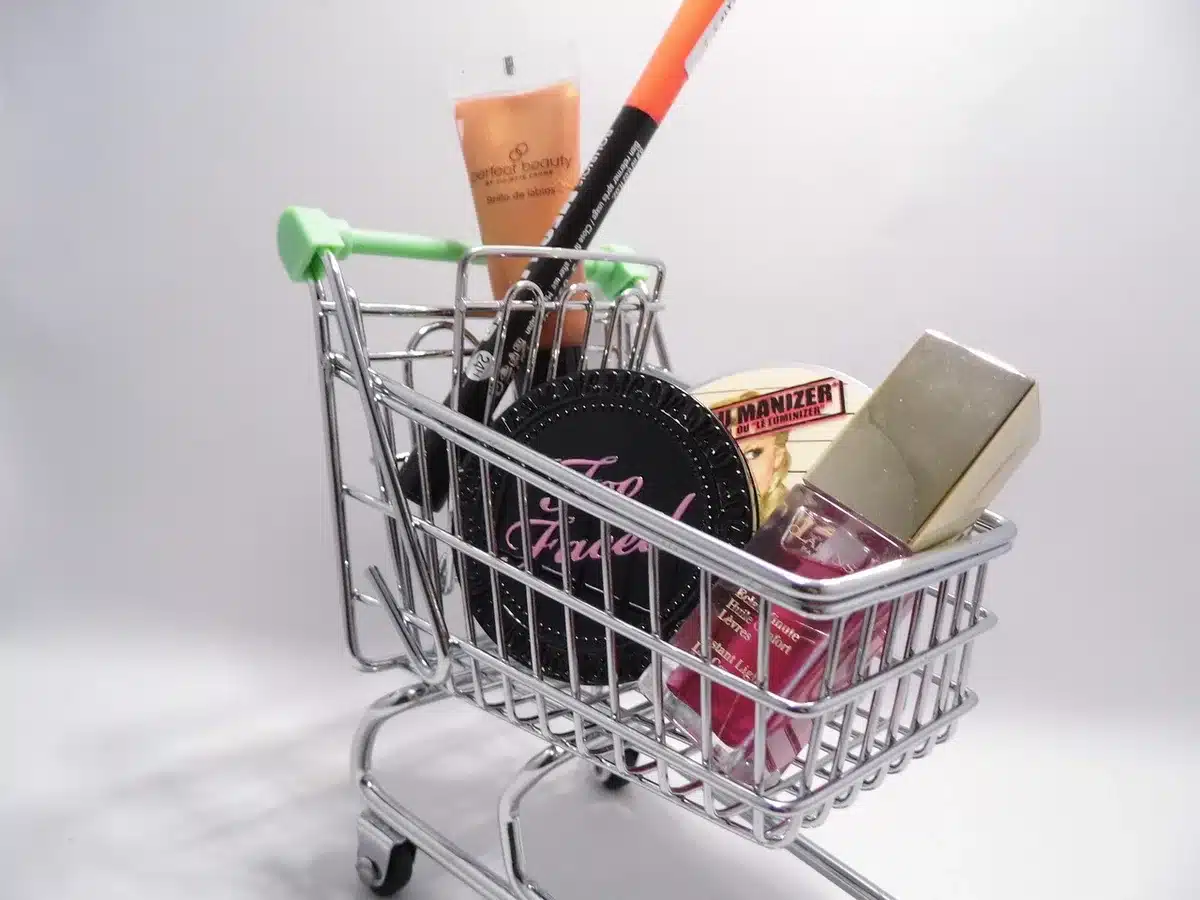 anonymous shopper holding a generic product box in a living room with a laptop open to an online store