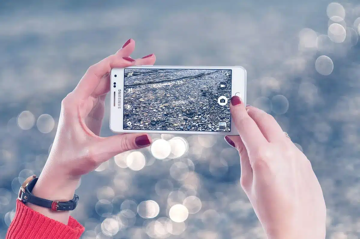 An anonymous hand holding a small credit-card-sized device near a smartphone, magnetically attached to the phone back, plain background, no brands