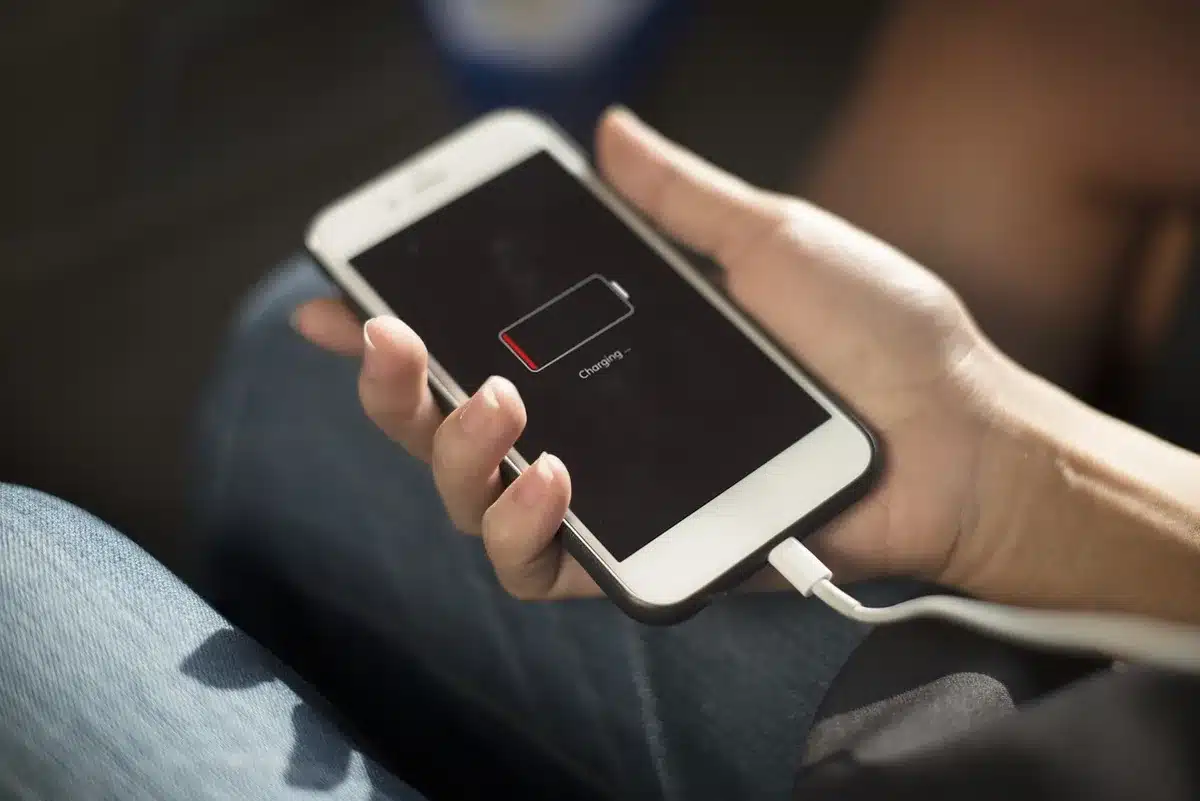 A compact unbranded portable battery on a plain table, a small smiling robot-style LED face visible on its surface, cable beside it