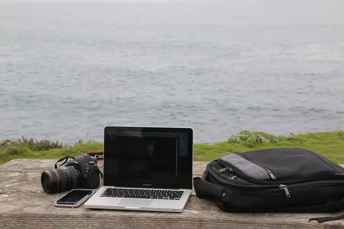 Empty study desk with an anonymous closed 14-inch laptop, a small backpack and a compact wireless mouse beside it