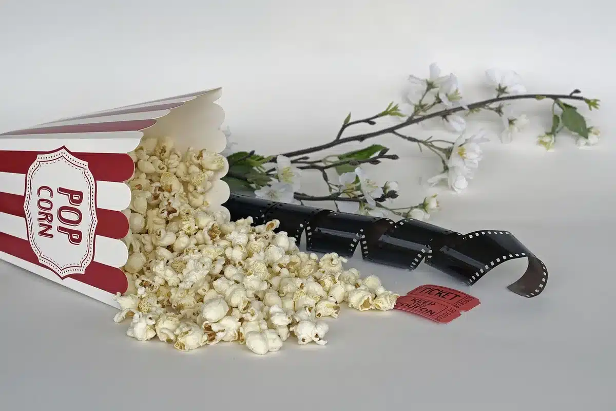 Manos sujetando entradas de cine genéricas con butacas desenfocadas al fondo