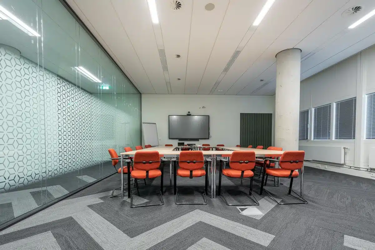 Sala de reuniones institucional sin personas con mesas y micrófonos