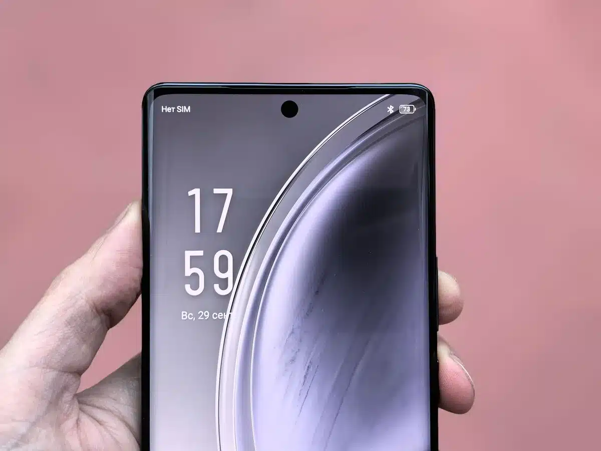 Wide close-up of an unbranded modern smartphone face-up on a clean table, screen on showing a generic colorful wallpaper, no logos or text