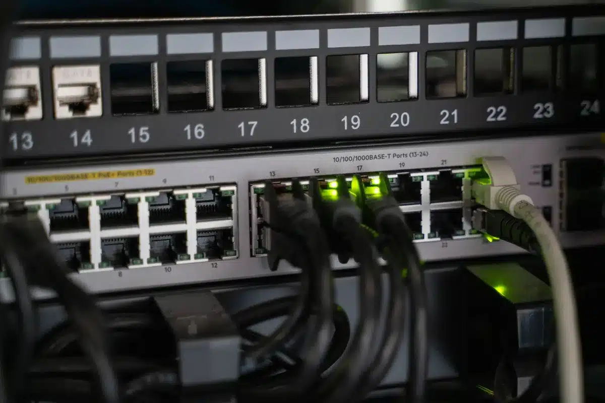A dim empty server room with a single unplugged network cable coiled on the floor, racks standing silent and blinking indicator lights off; no people, no logos