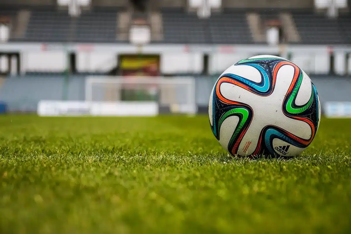 Close-up of anonymous player boots on turf, rain droplets mid-air, stadium lights blurred in background