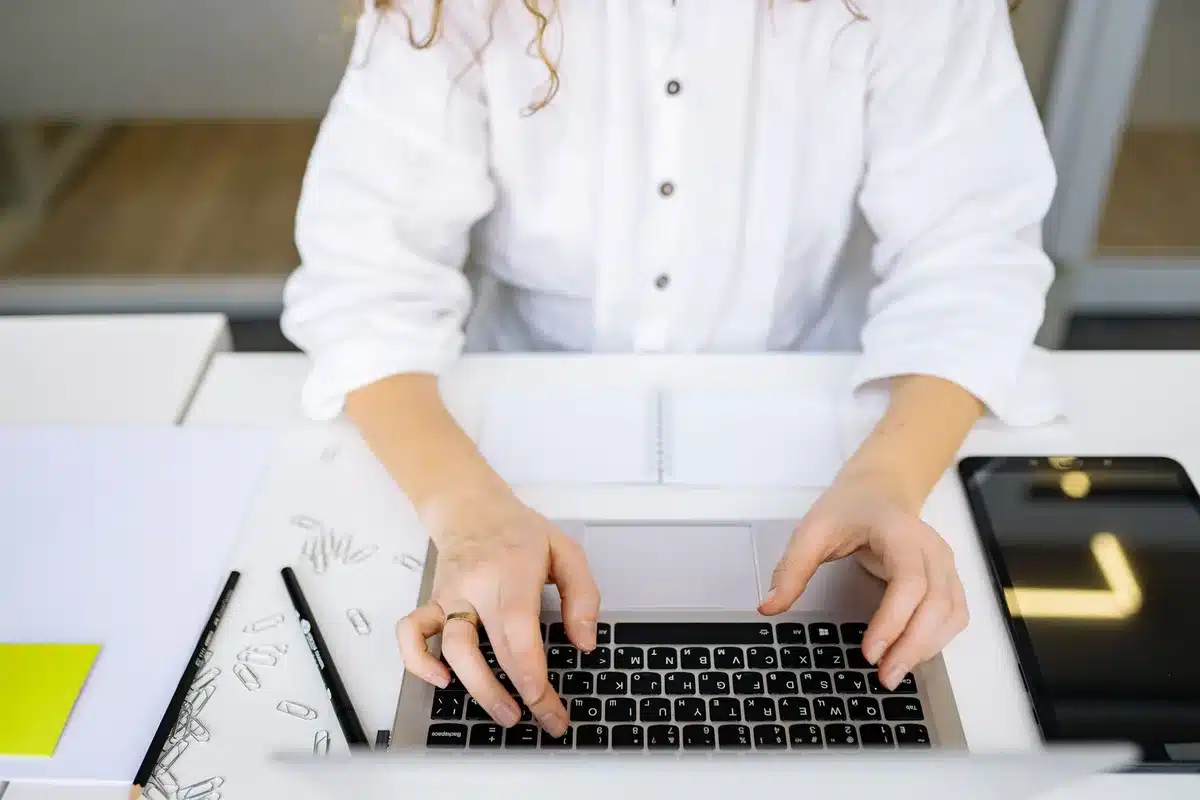 Close-up of anonymous hands typing on a laptop with a simple AI chat window blurred on screen, no logos visible