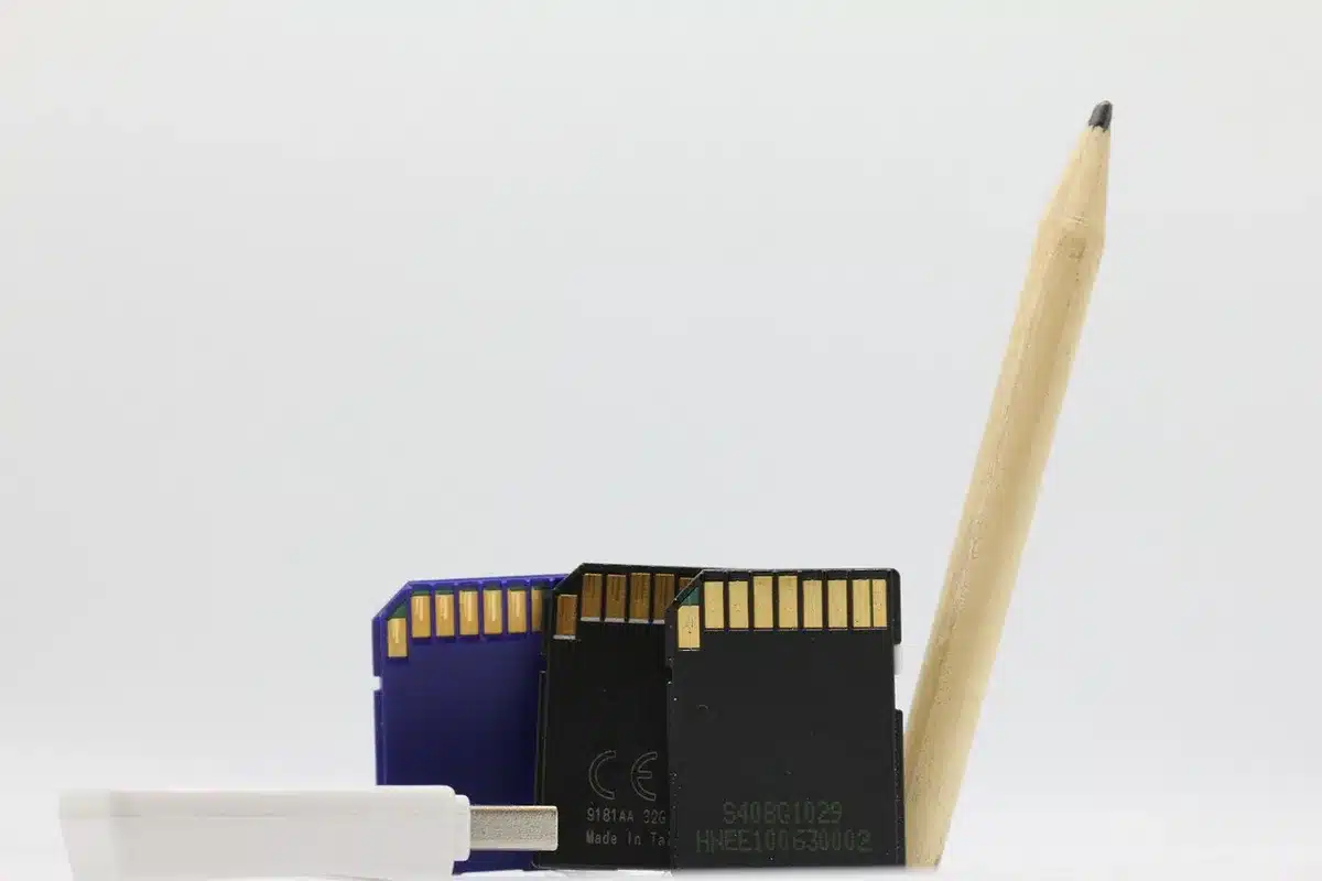 A close-up of hands plugging a USB-C cable into an anonymous portable drive next to a plain folder labeled 'photos' on screen